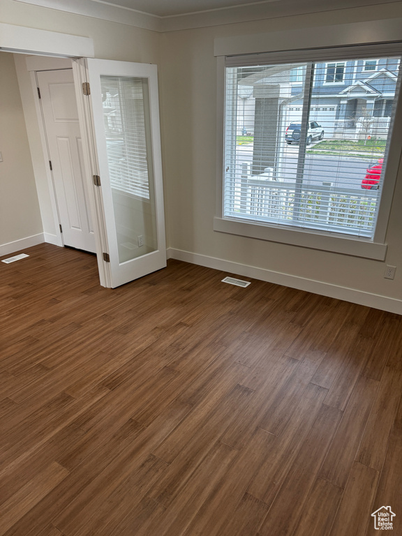 Spare room featuring dark wood-type flooring, a healthy amount of sunlight, baseboards, and visible vents