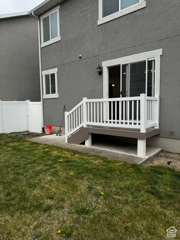 Back of house featuring stucco siding, a lawn, and fence