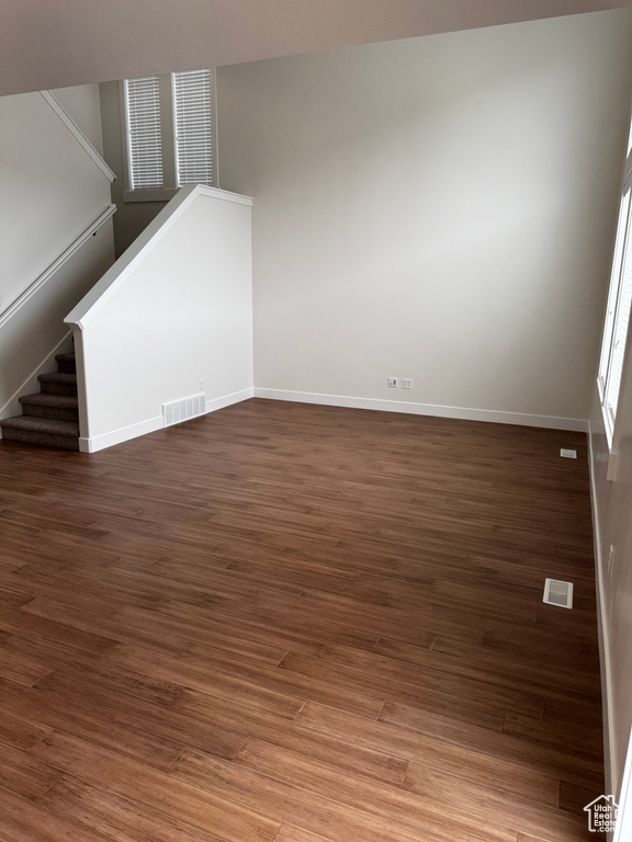 Unfurnished living room with wood finished floors, visible vents, and baseboards