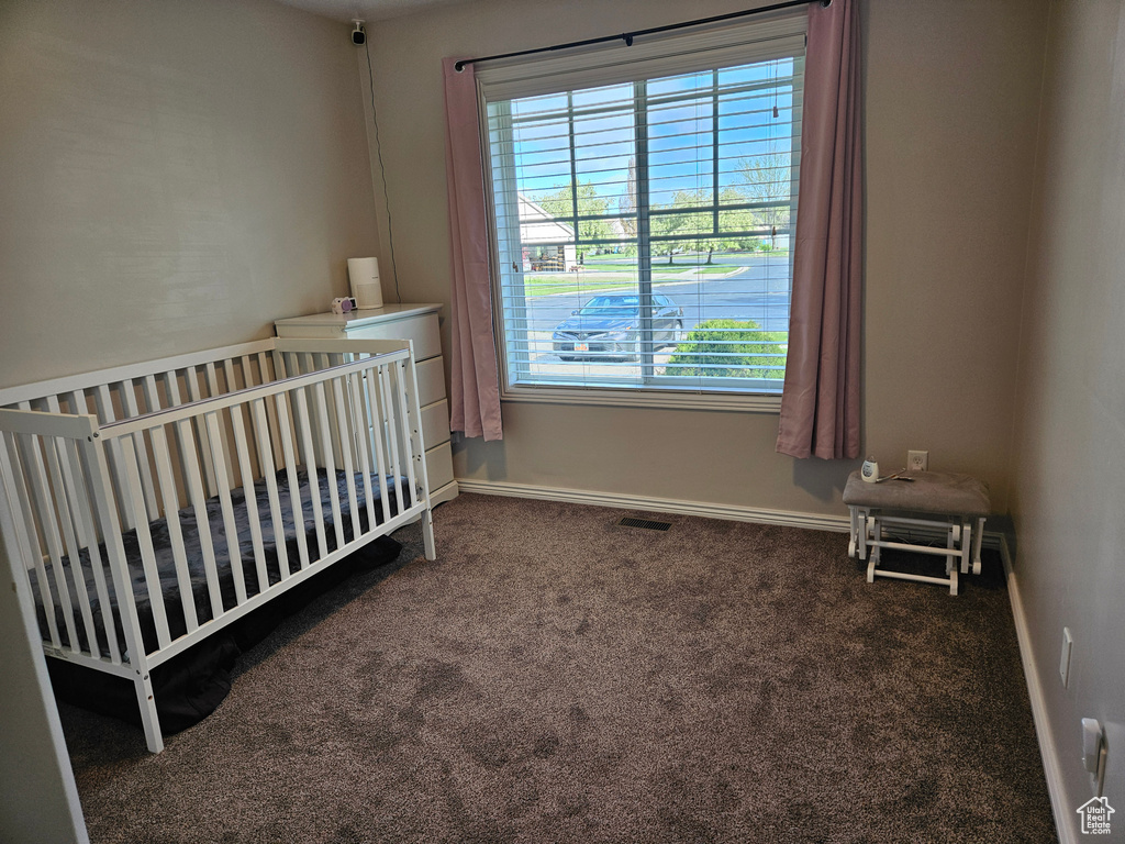 Bedroom featuring a nursery area, visible vents, and carpet