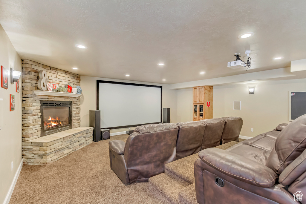 Cinema room with recessed lighting, a stone fireplace, baseboards, and light carpet