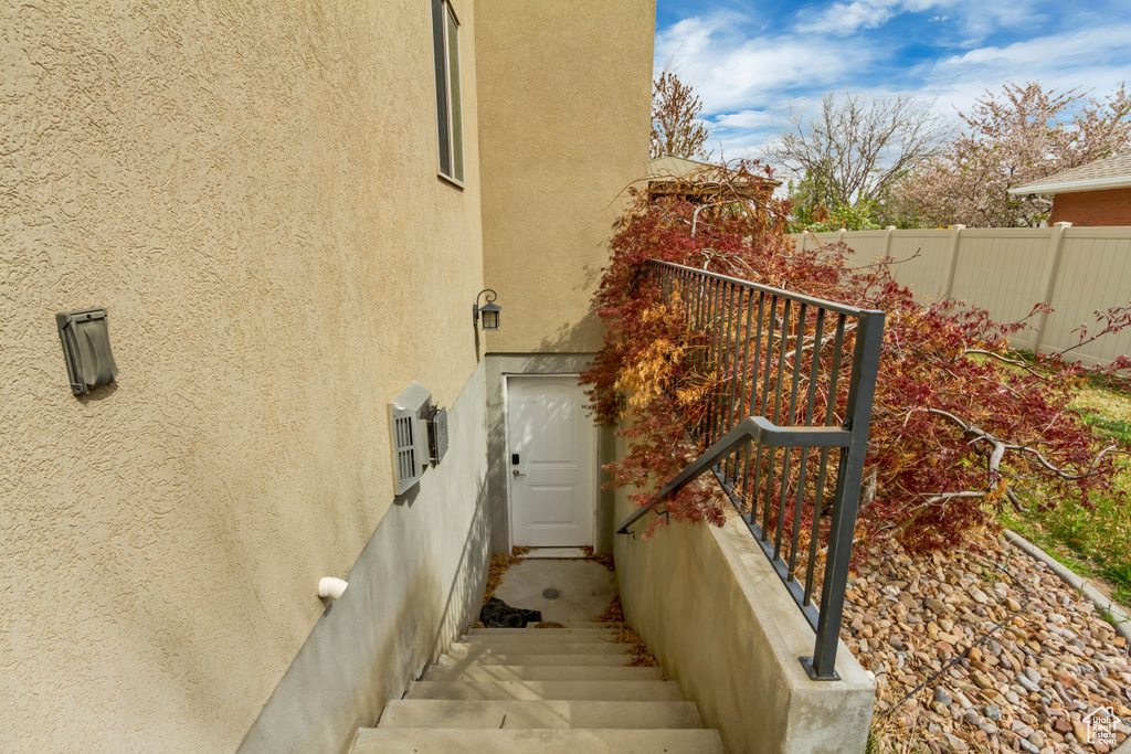 View of side of home featuring fence and stucco siding