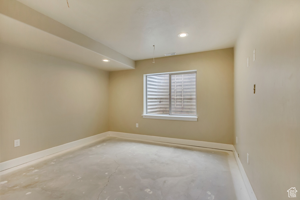 Empty room with concrete floors, visible vents, baseboards, and recessed lighting