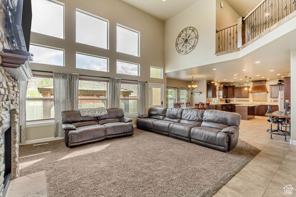 Living room featuring a wealth of natural light, a towering ceiling, a fireplace, and a notable chandelier