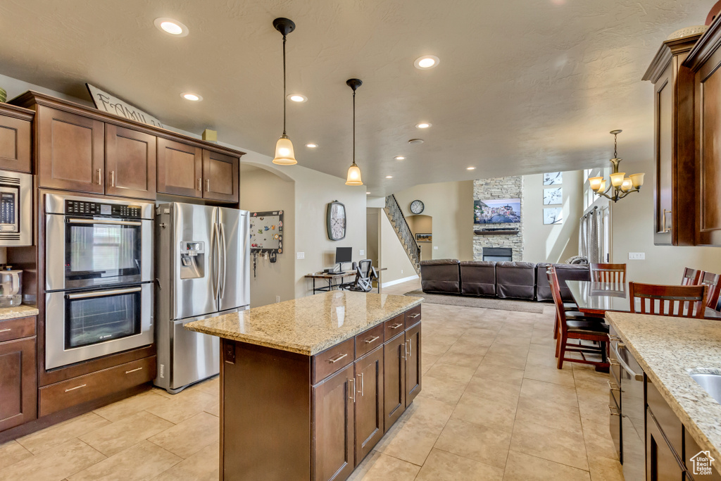 Kitchen with stainless steel appliances, a fireplace, recessed lighting, and hanging light fixtures