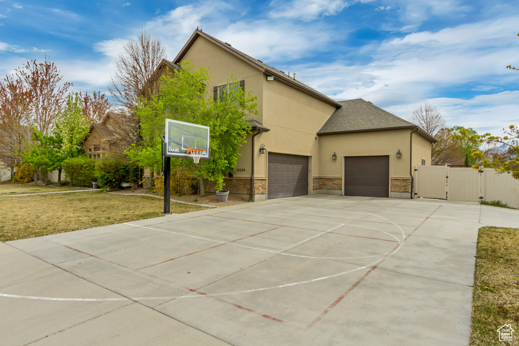 View of basketball court featuring fence, a gate, and a yard