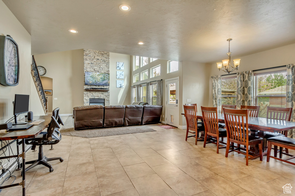 Dining room featuring a notable chandelier, a stone fireplace, light tile patterned flooring, and recessed lighting