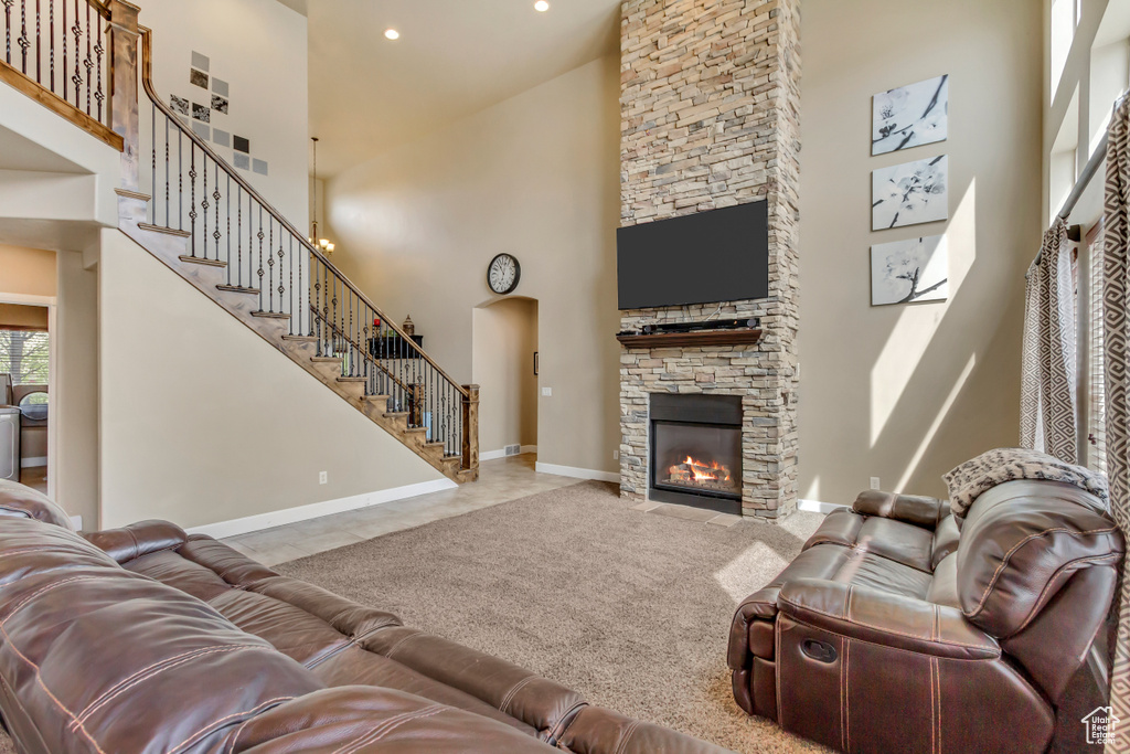 Living room with recessed lighting, a towering ceiling, a stone fireplace, baseboards, and stairs