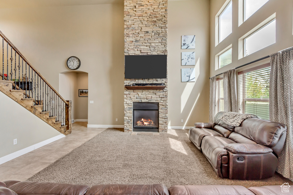 Tiled living room with baseboards, a towering ceiling, and a fireplace