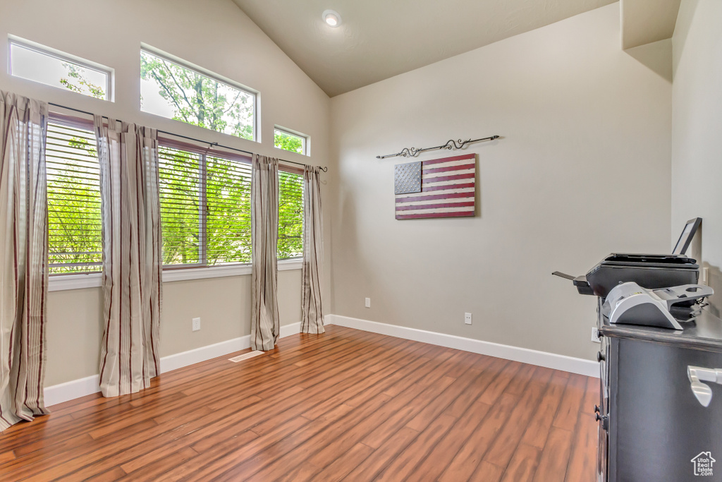 Interior space with high vaulted ceiling, baseboards, and wood finished floors
