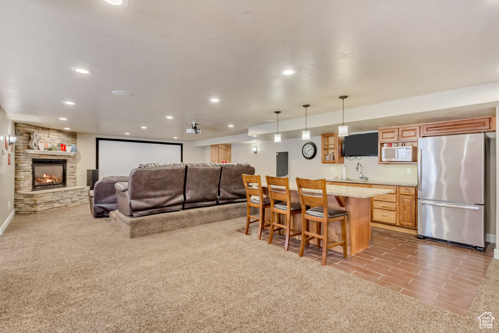 Interior space featuring open floor plan, freestanding refrigerator, recessed lighting, white microwave, and a kitchen bar