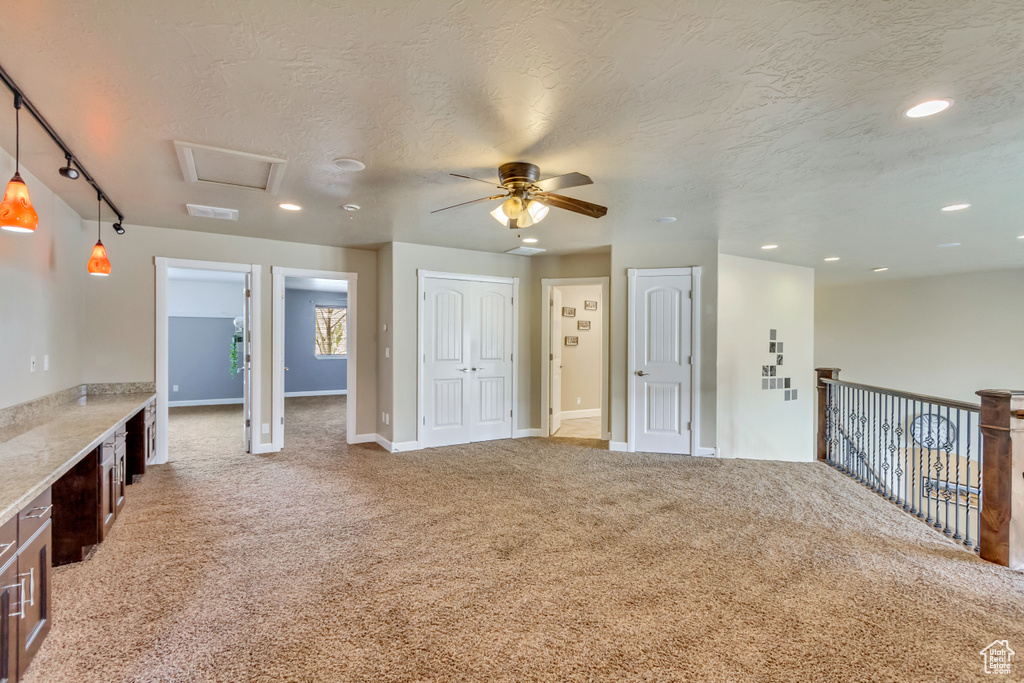 Interior space with a textured ceiling, visible vents, recessed lighting, light colored carpet, and ceiling fan