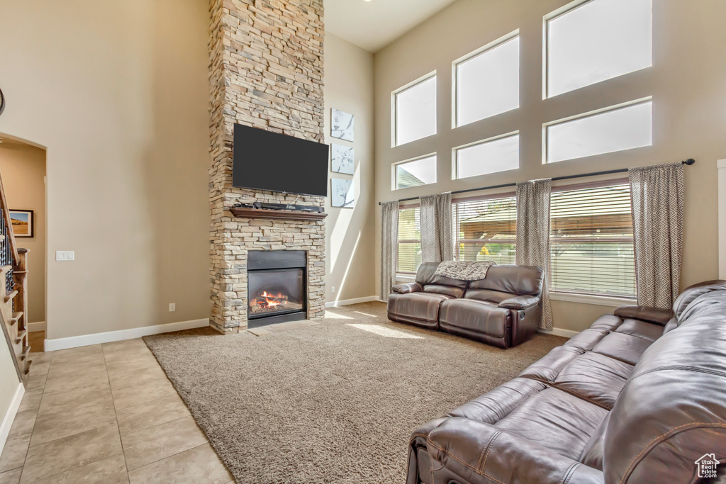 Tiled living room with baseboards, a stone fireplace, and a towering ceiling