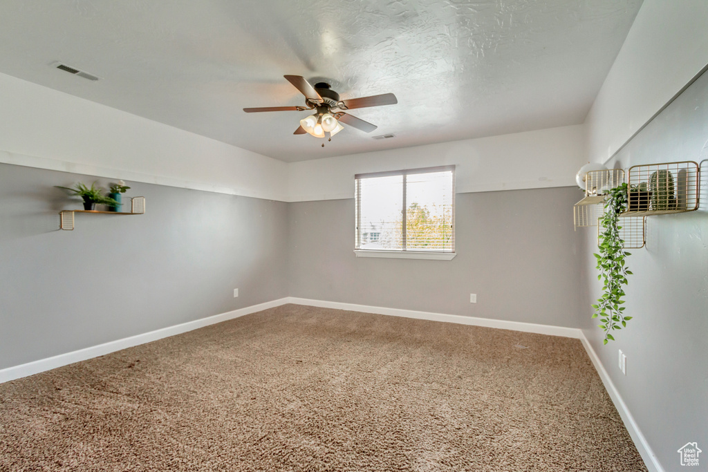Unfurnished room with visible vents, a ceiling fan, baseboards, and carpet floors