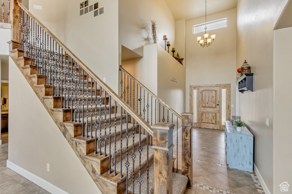 Stairs with a chandelier, a high ceiling, and baseboards