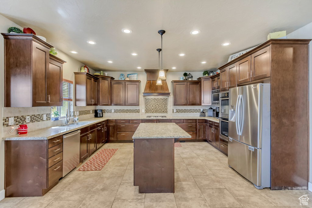 Kitchen with backsplash, a sink, a center island, appliances with stainless steel finishes, and custom range hood