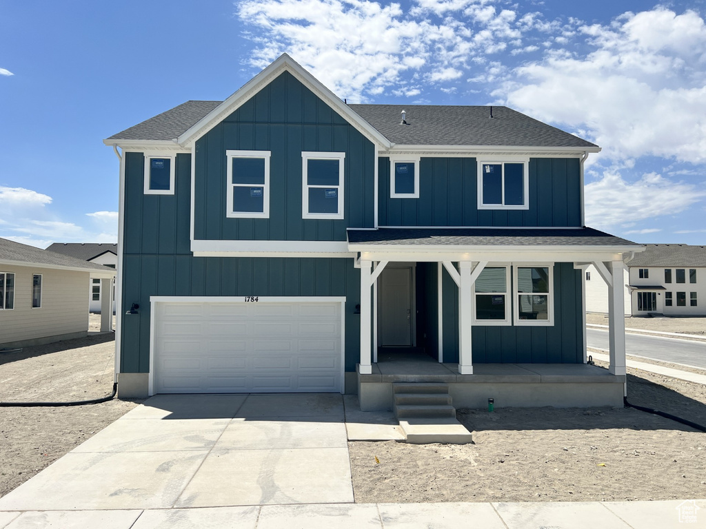 View of front of property featuring covered porch, an attached garage, concrete driveway, and board and batten siding