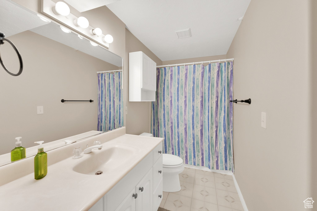 Full bath with vanity, toilet, baseboards, marble look tile flooring, and curtained shower