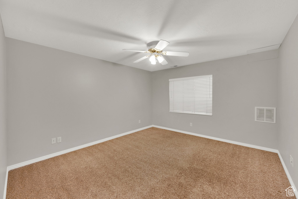 Empty room featuring carpet flooring, ceiling fan, and baseboards