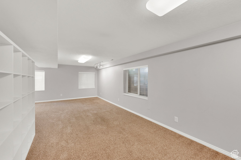 Basement featuring light colored carpet and baseboards