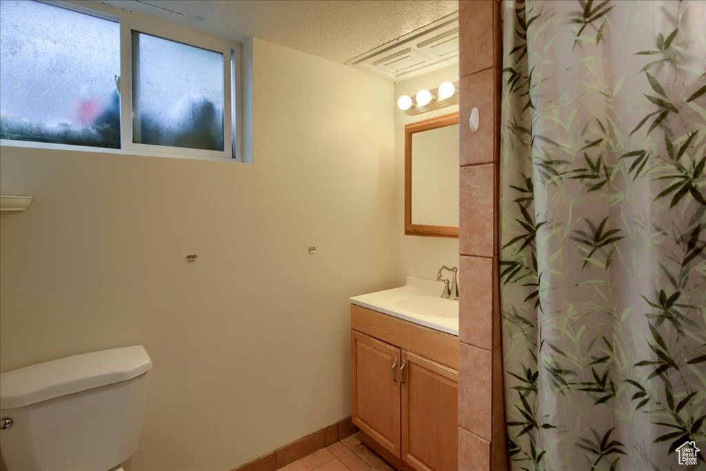 Bathroom with baseboards, vanity, tile patterned flooring, and toilet