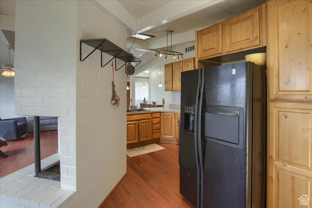 Kitchen with a sink, black fridge with ice dispenser, light countertops, dark wood-style flooring, and visible vents