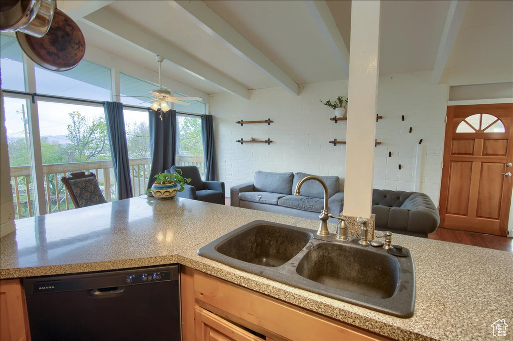 Kitchen featuring dishwasher, open floor plan, a sink, and light countertops