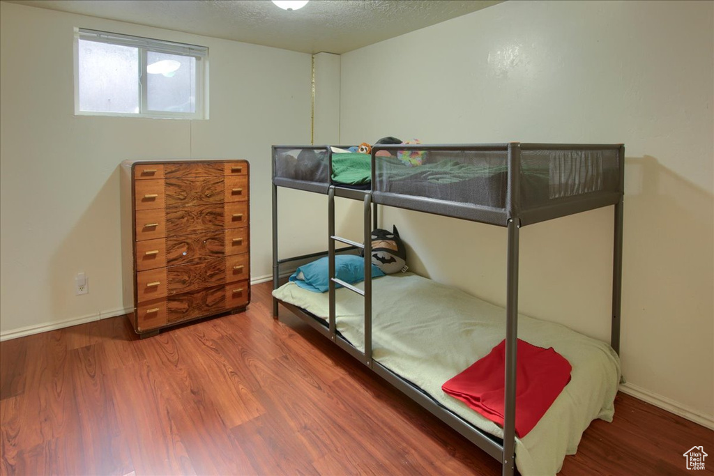 Bedroom featuring wood finished floors, a textured ceiling, and baseboards