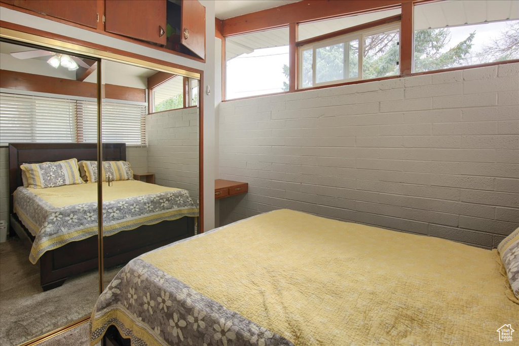 Carpeted bedroom with a closet and brick wall