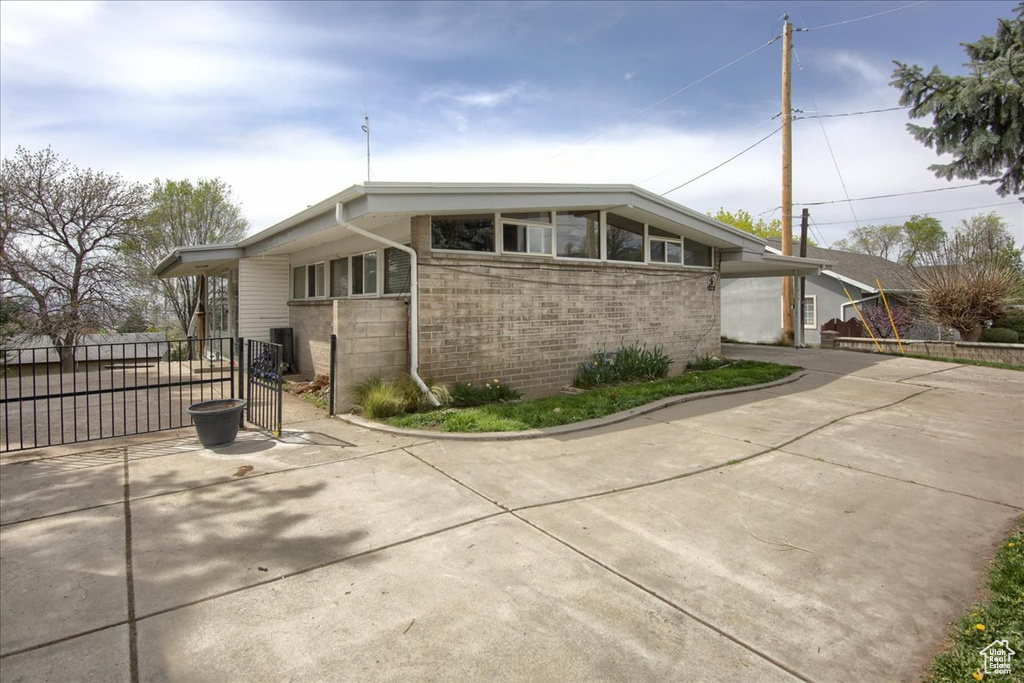 Mid-century home with fence, driveway, and brick siding