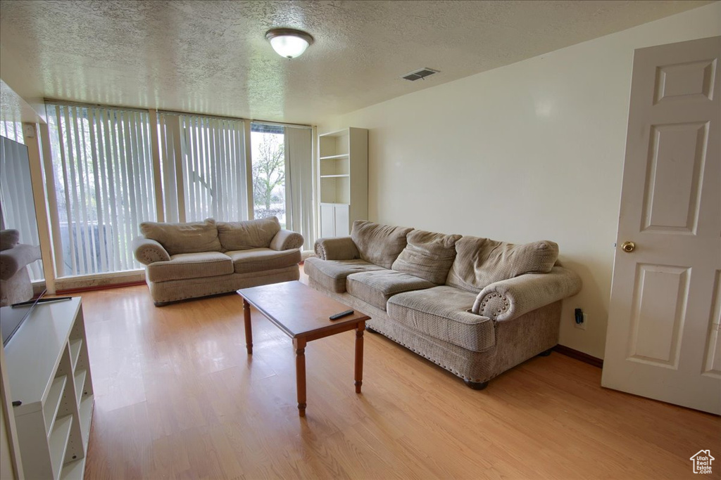 Living area with visible vents, a textured ceiling, and light wood-style floors