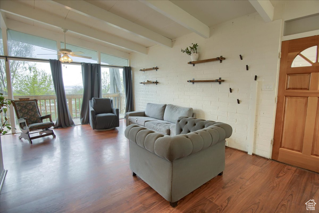 Living area featuring a ceiling fan, wood finished floors, beamed ceiling, and floor to ceiling windows