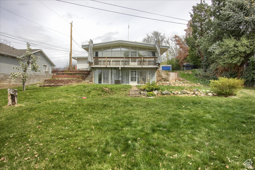 Rear view of property with a lawn, stairway, and a deck