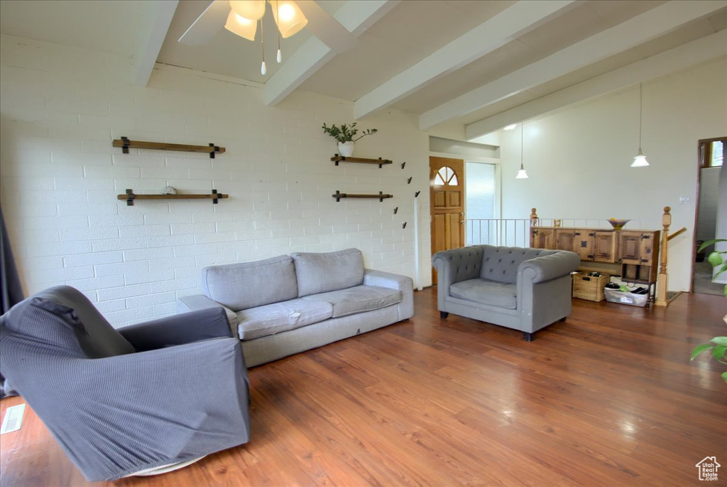 Living area featuring wood finished floors, vaulted ceiling with beams, and a ceiling fan