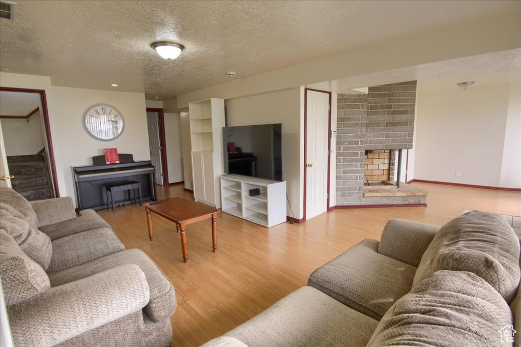 Living room featuring a textured ceiling, baseboards, visible vents, wood finished floors, and stairway