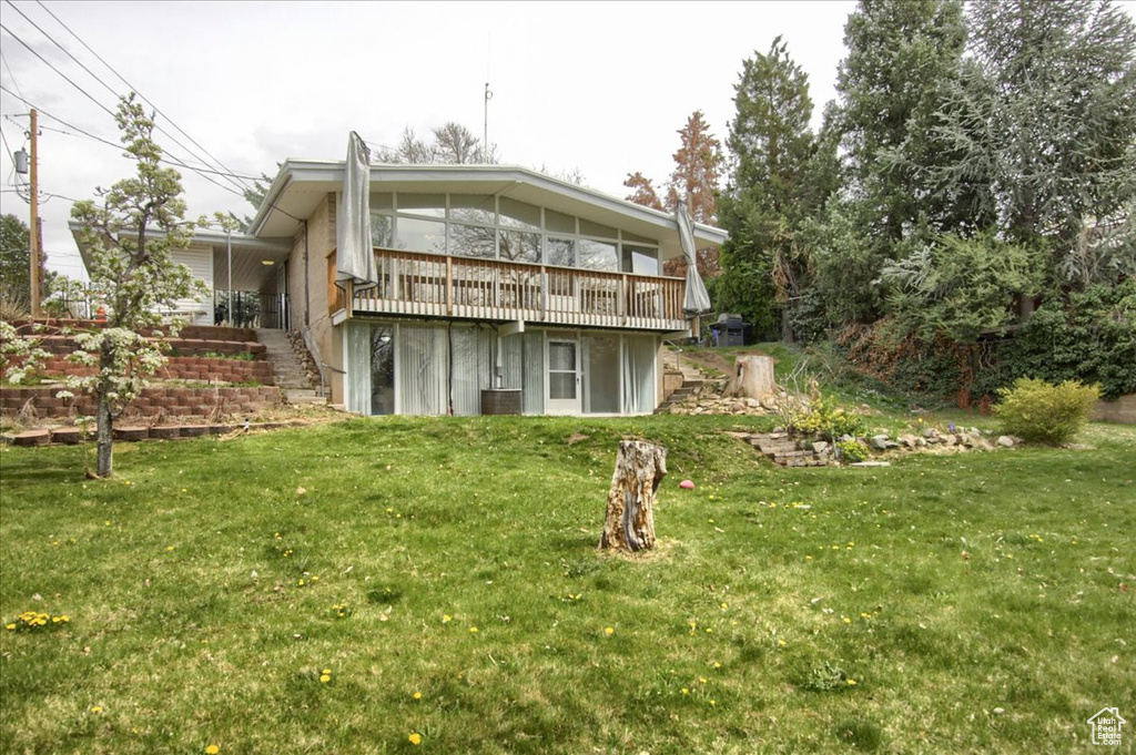 Back of property featuring a lawn, a wooden deck, a sunroom, and stairs