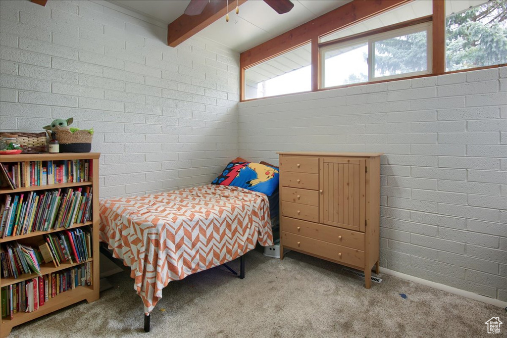 Carpeted bedroom with a ceiling fan and beam ceiling
