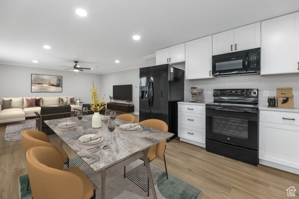 Kitchen with light wood finished floors, crown molding, white cabinetry, ceiling fan, and black appliances