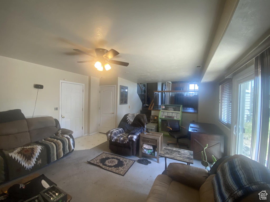 Living room featuring a ceiling fan, carpet flooring, and a wood stove