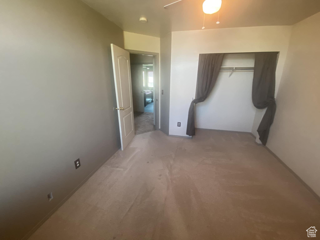 Unfurnished bedroom featuring light colored carpet, a ceiling fan, and a closet