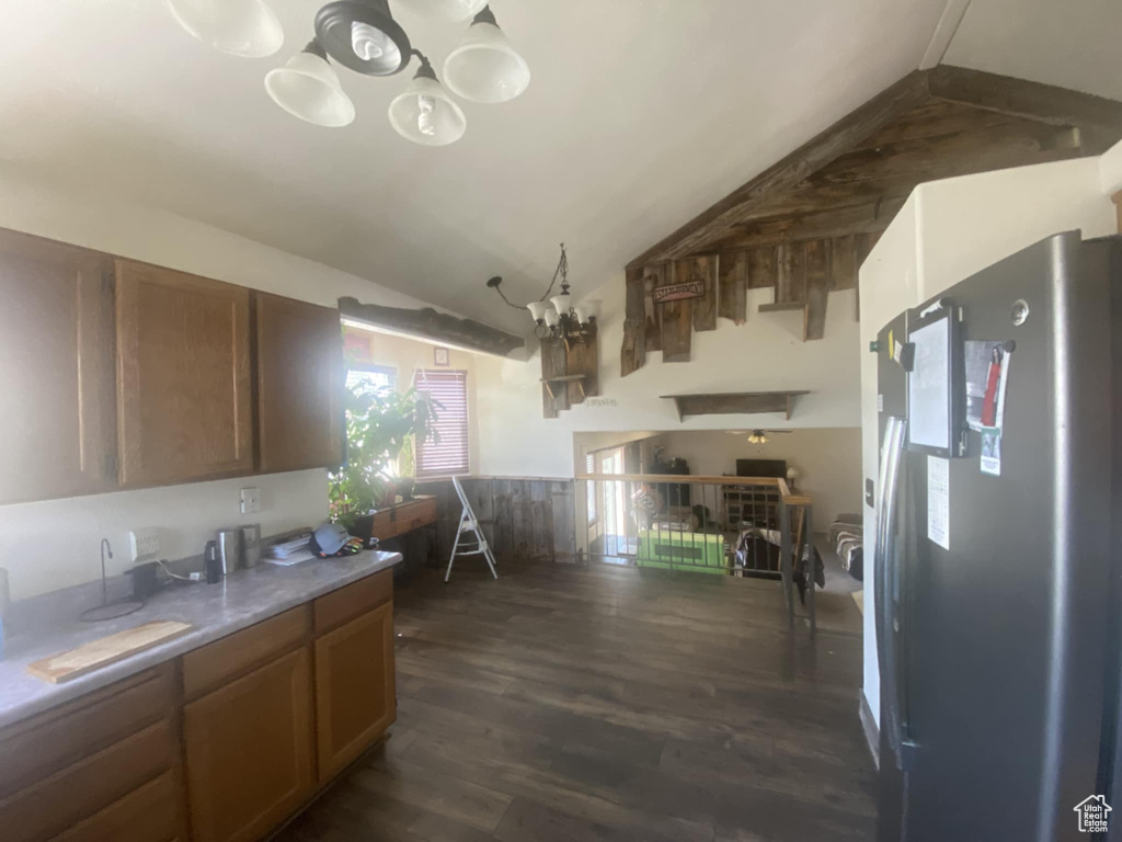 Kitchen with freestanding refrigerator, a chandelier, dark wood-type flooring, lofted ceiling, and brown cabinets