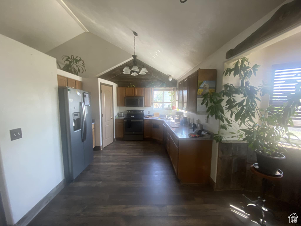 Kitchen with appliances with stainless steel finishes, dark wood-type flooring, lofted ceiling, brown cabinets, and a chandelier