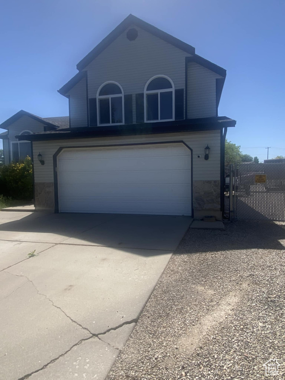 View of front of property with a garage, concrete driveway, and stone siding