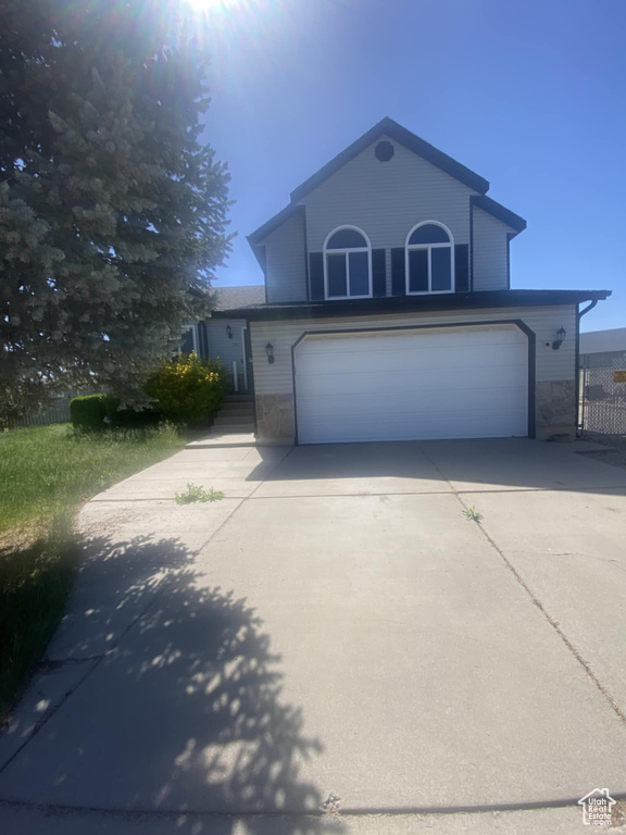 Traditional-style home with an attached garage, concrete driveway, and stone siding