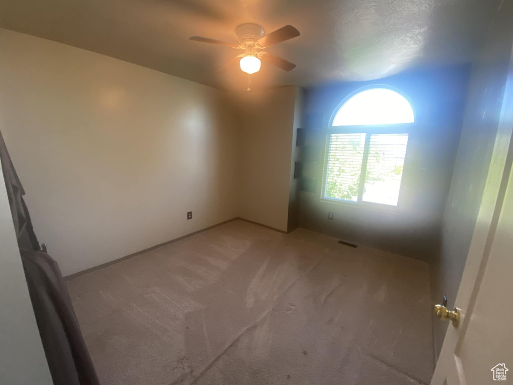 Unfurnished room with light colored carpet and a ceiling fan