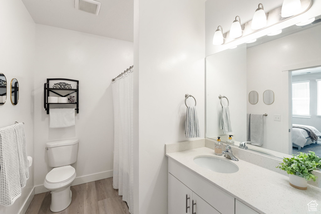 Ensuite bathroom with wood finished floors, ensuite bathroom, vanity, toilet, and visible vents