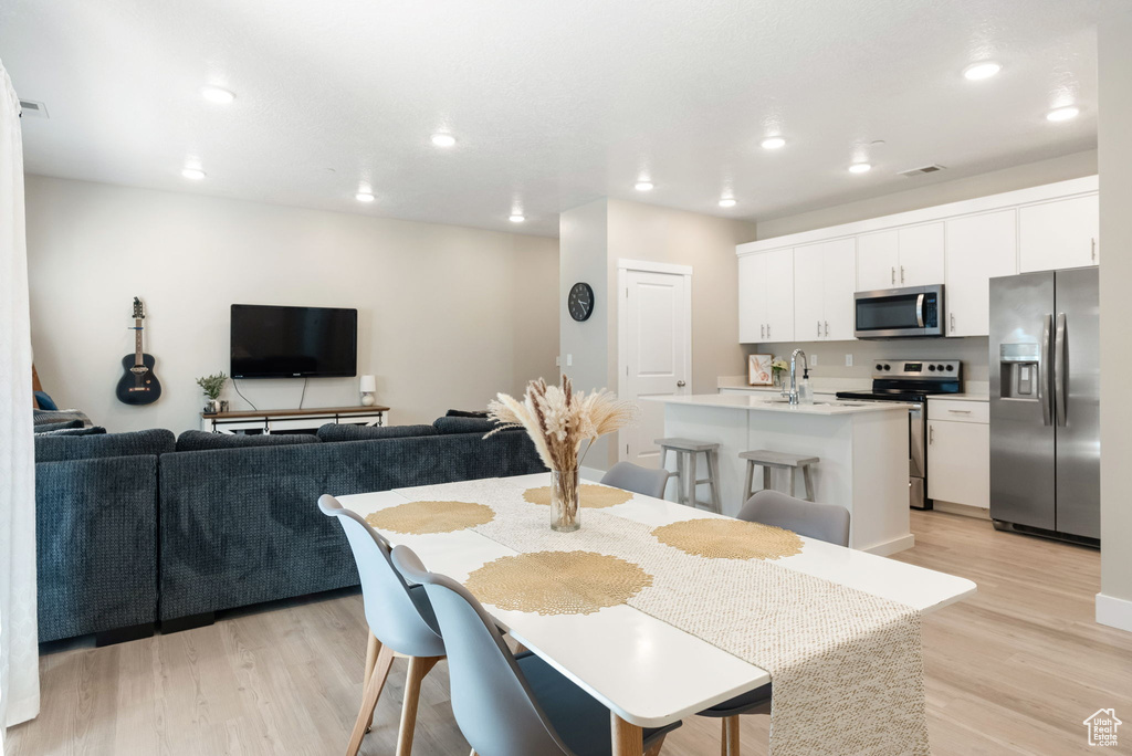 Dining area with light wood-type flooring, visible vents, and recessed lighting