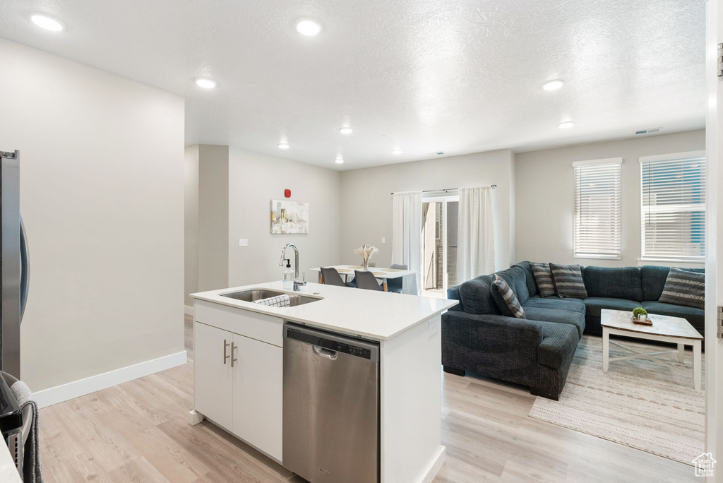 Kitchen with a sink, light wood-type flooring, dishwasher, a center island with sink, and white cabinets