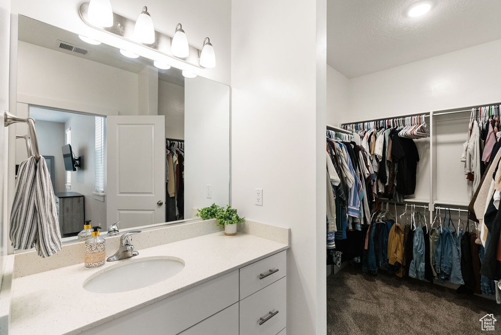 Bathroom featuring a spacious closet, visible vents, and vanity