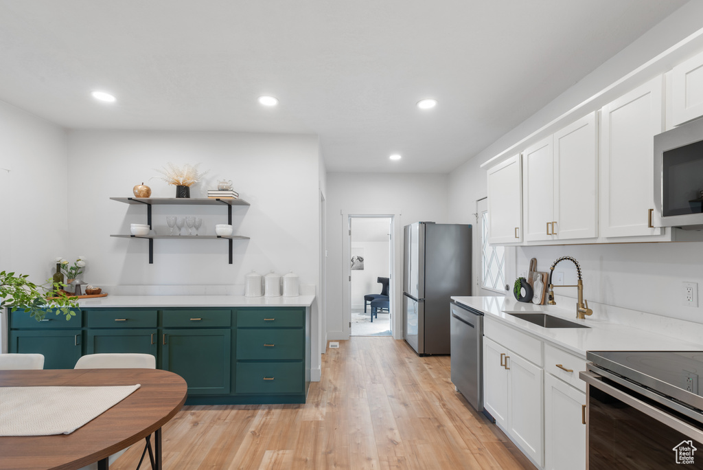 Kitchen with white cabinets, stainless steel appliances, a sink, and green cabinets